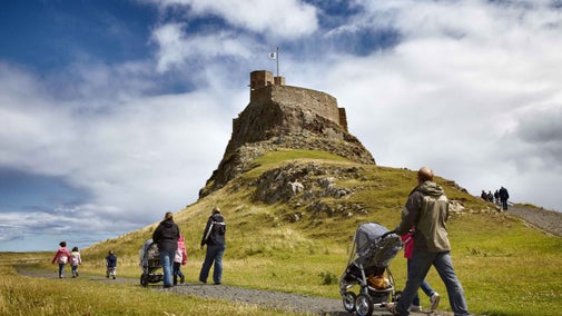 Visitors pushing buggies approaching Lindisfarne Castle